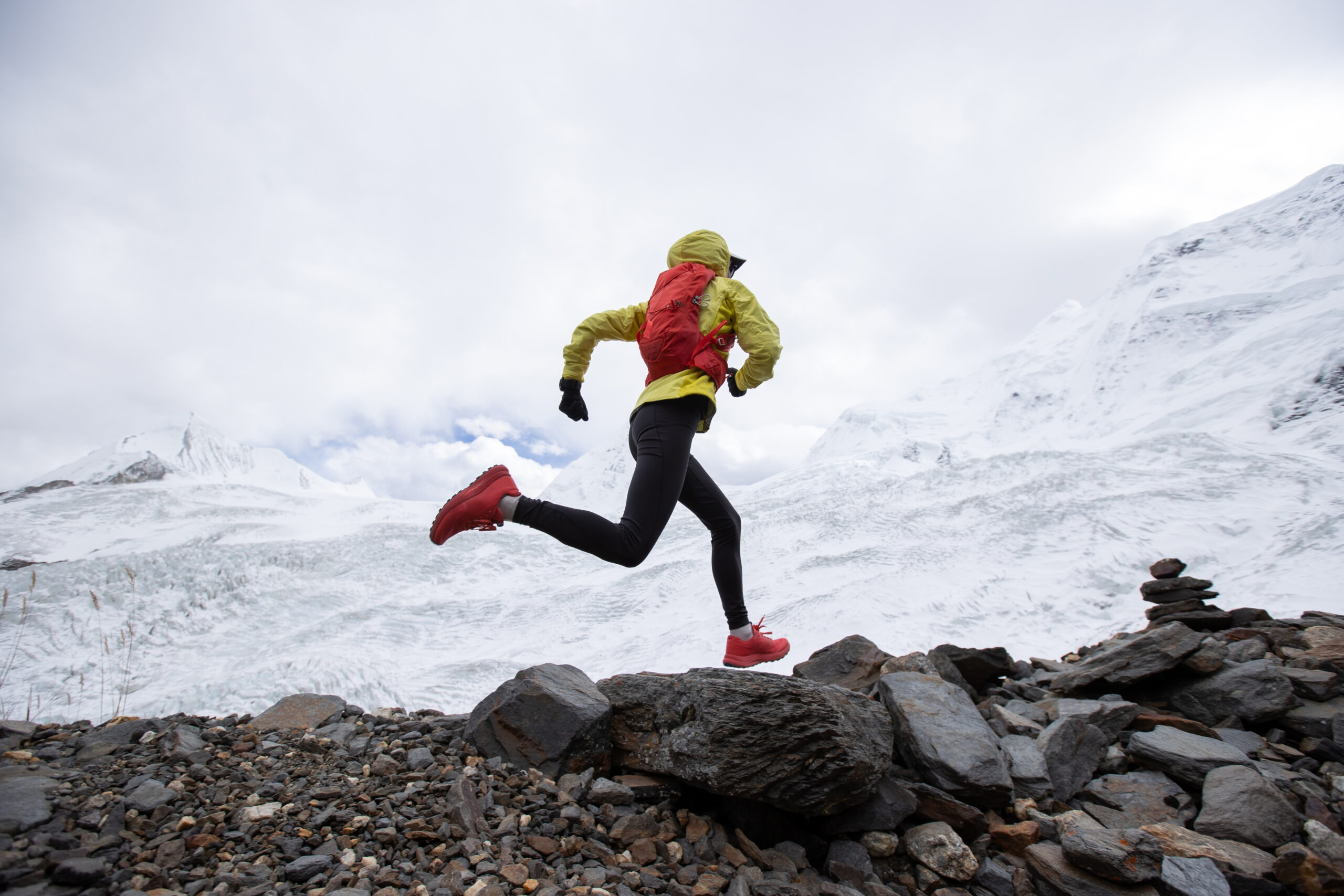 Coureur de trail parcourant un sentier de haute montagne un jour d'automne pluvieux pendant une séance d'entraînement.